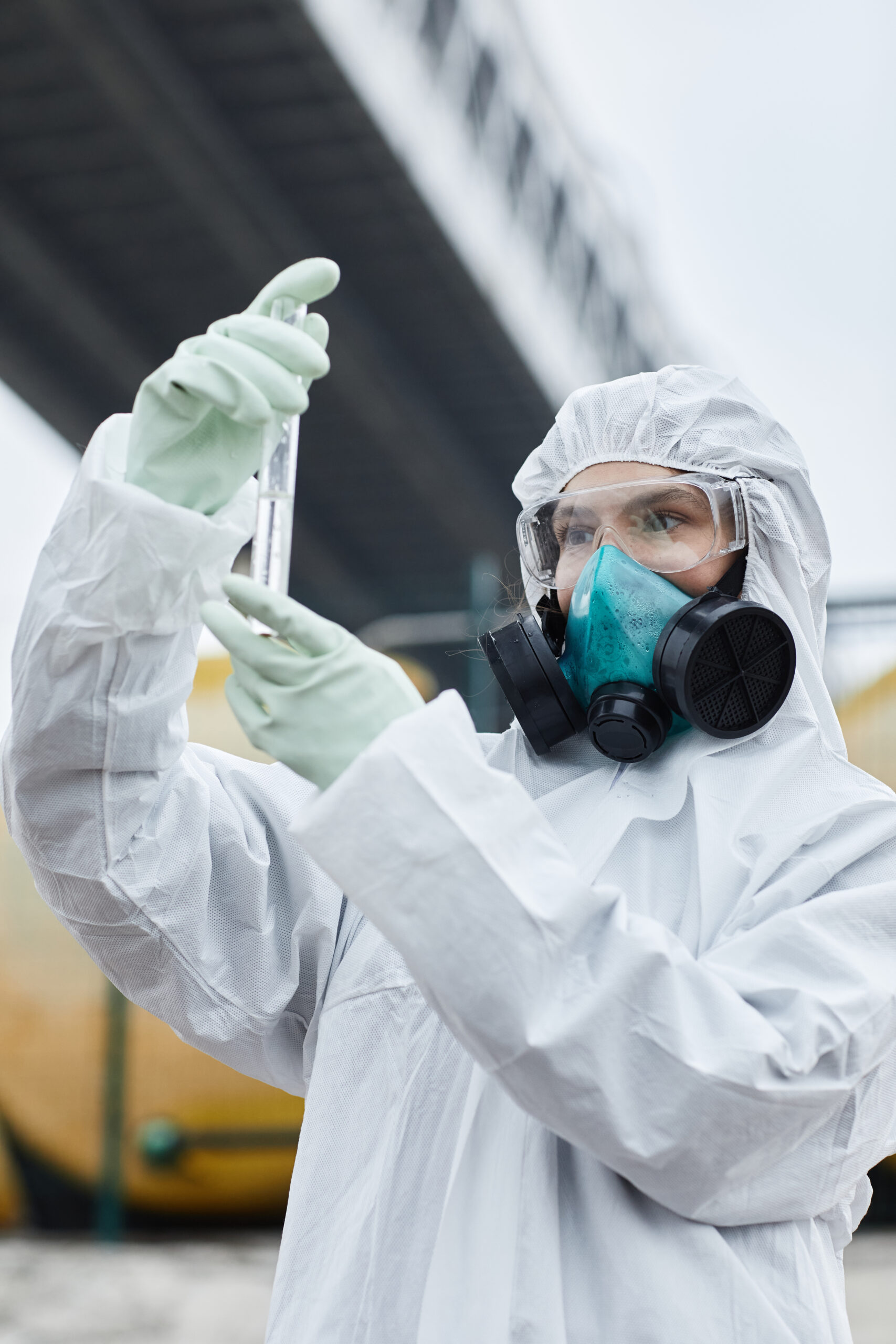 Fachfrau im Schutzanzug entnimmt Materialproben